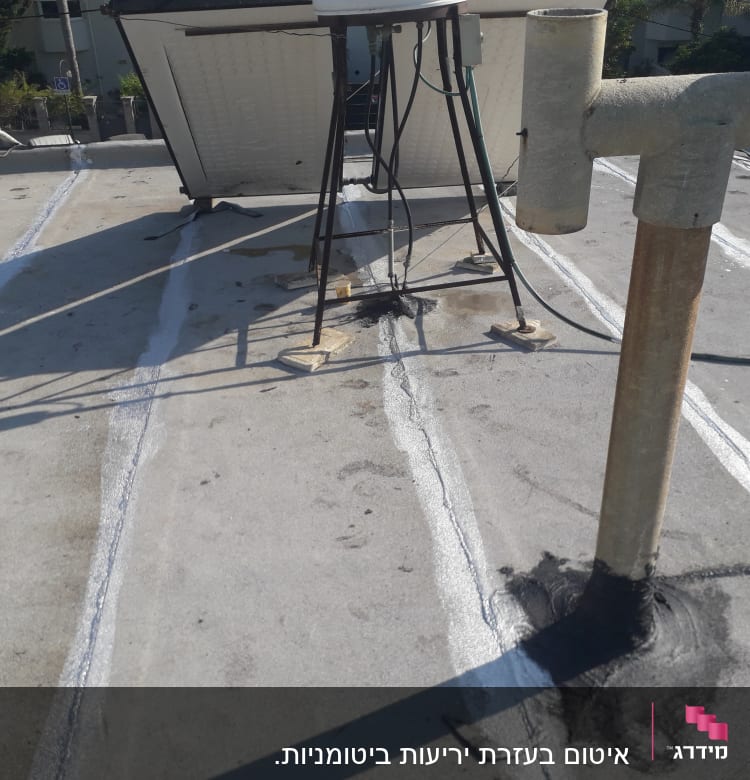 איטום גג עם חומר שחור סביב צינור